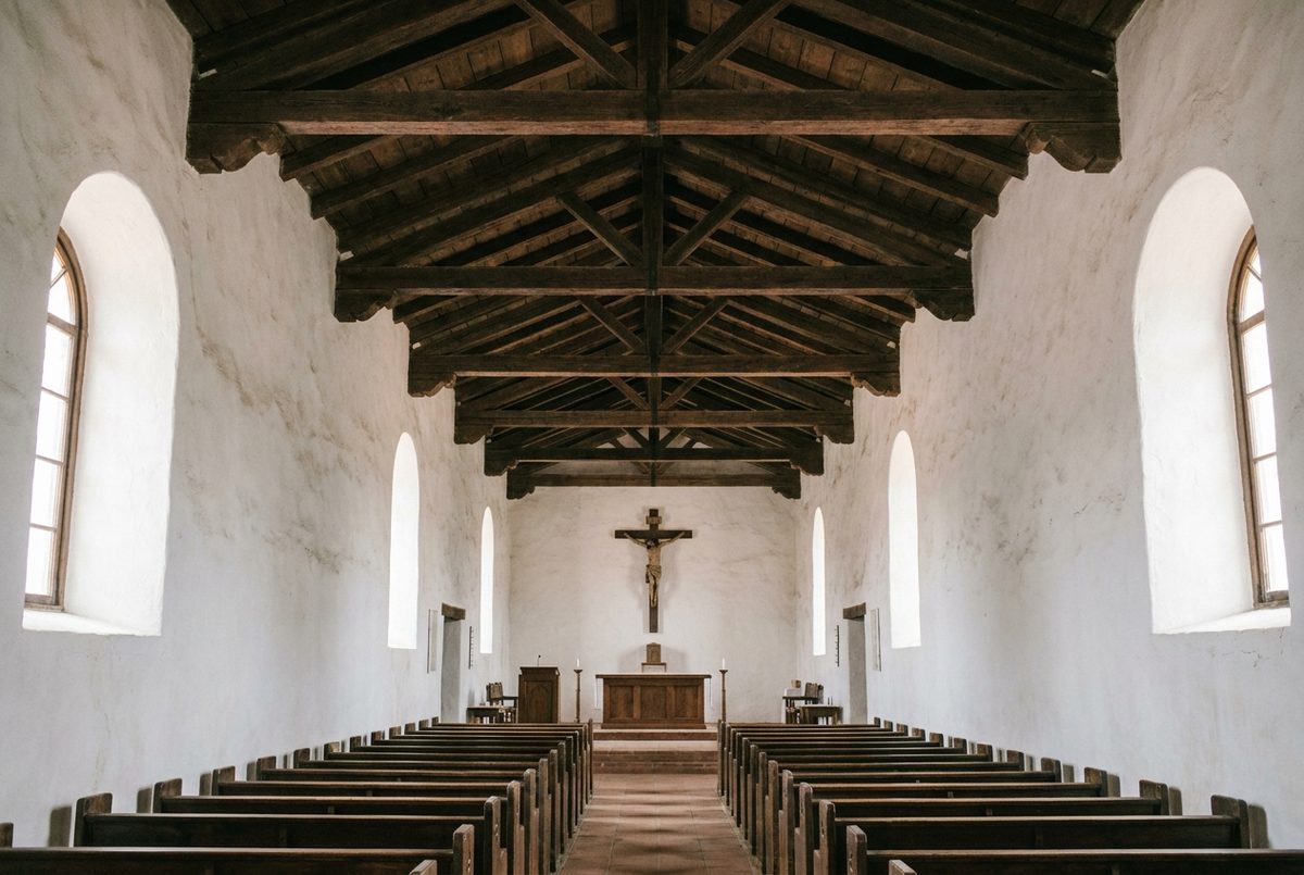 Mission-style church interior with white walls, wooden ceiling beams and pews